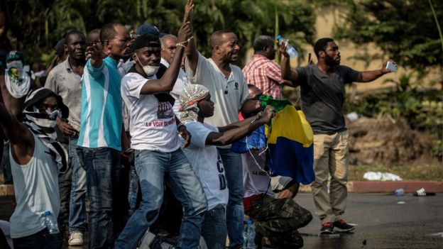 Anhänger des gabunischen Oppositionsführers Jean Ping stellen Sicherheitskräfte gegenüber